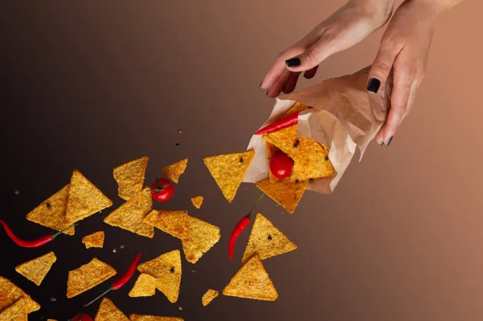 flying spicy mexican nachos on a beige background levitation hands in the frame selective focus
