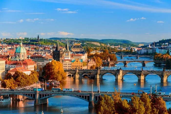 view of the vltava river and charle bridge with red foliage, prague, czech republic