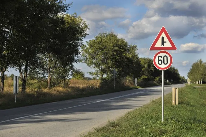 road sign speed limit sixty under cloudy blue sky