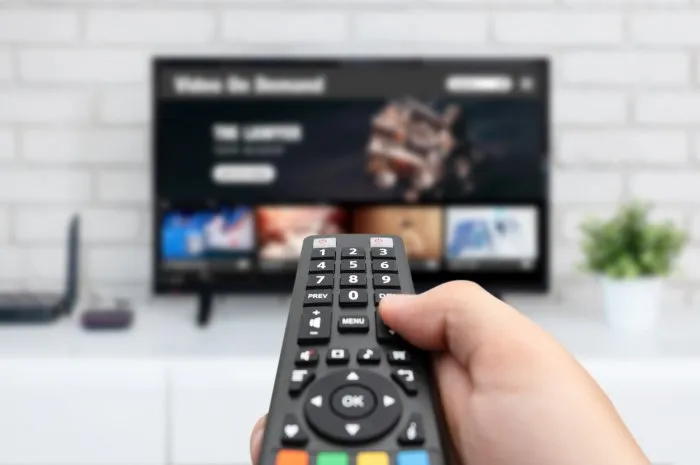 man watching tv, remote control in hand vod service on tv