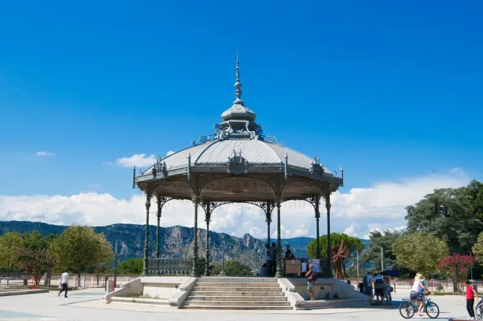 peynet kiosk in valence with hills at the background, small group of people walking, cycling around