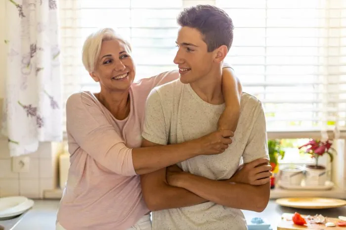 mother hugging her teenage son in the kitchen