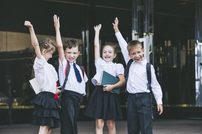 beautiful school children active and happy on the background of school in uniform