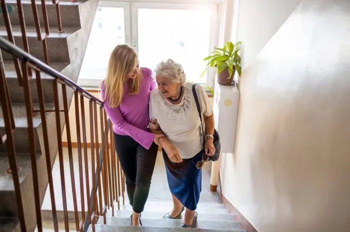 caregiver helping senior woman climb staircase