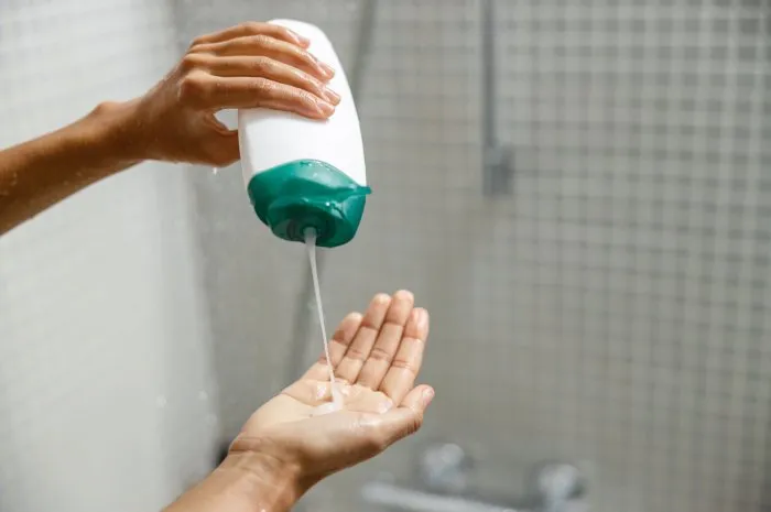 woman pouring shower gel on her hand when taking shower hygiene concept high quality photo
