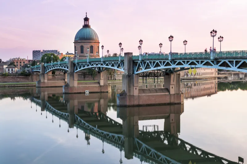 saint-pierre bridge reflecting in garonne river and dome de la grave at sunset in toulouse, france