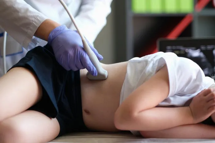doctor conducting ultrasound examination of kidneys to child in clinic diagnosis of pyelonephritis in children concept