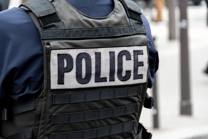 close-up 'police' marking written on the back of a bulletproof vest worn by a french police officer on a street in paris, france concepts of law enforcement, crime, delinquency and criminal affairs