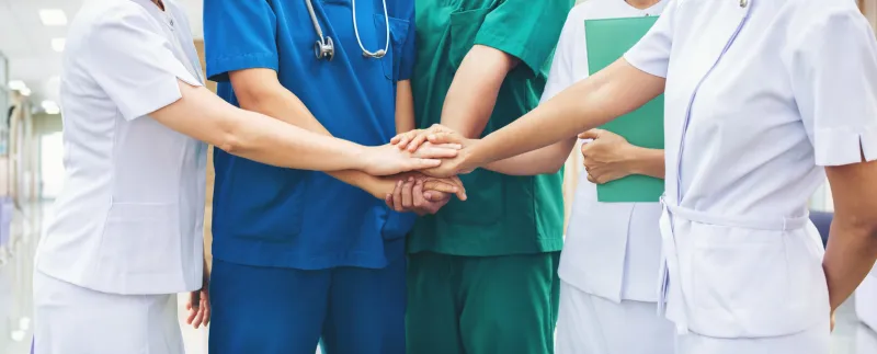 cooperation of people in the medical community teamwork with a hands together between the doctor in the green, blue uniform and nurses in white dress at hospital fight covid 19 virus healthy concept