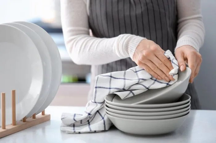 woman wiping plate with towel in kitchen