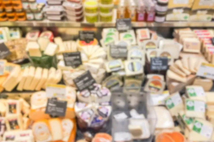 blurred image large variety of cheese to choose at cheese counter of american supermarket chain in irving, texas, usa defocused stack of fresh whole or slice cheese food abstract background
