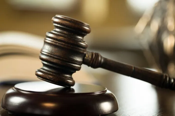 law and justice concept mallet of the judge, books, scales of justice gray stone background, reflections on the floor, place for typography courtroom theme