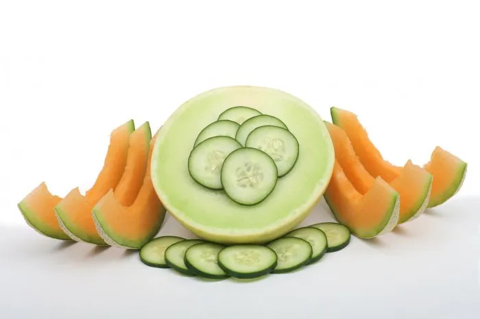color photograph of cantaloupe honet dew and sliced cucumber on a white backgound
