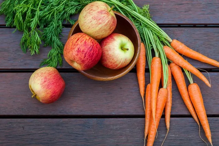 vegetables and fruits carrots, and apples on the wooden table