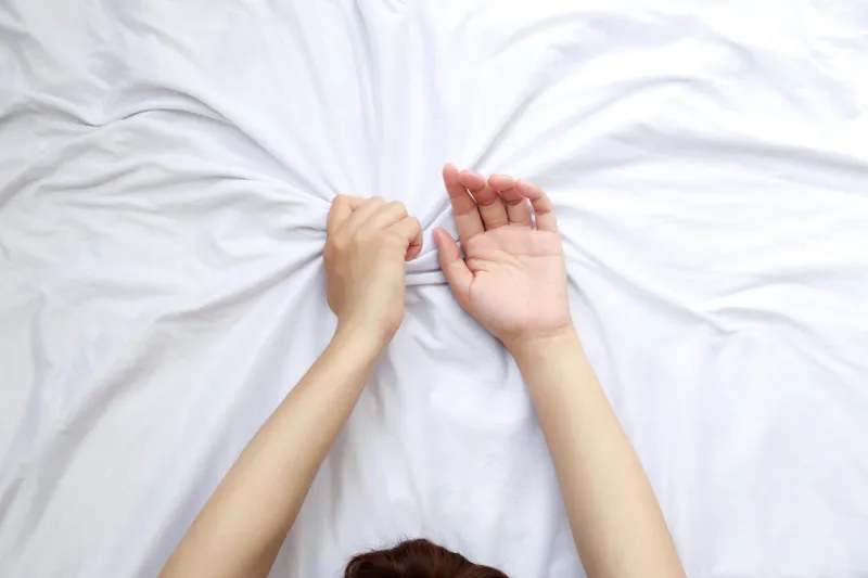 close up woman hands grasping the blanket in the moment of sexual pleasure or orgasm ecstasy sex creator concept