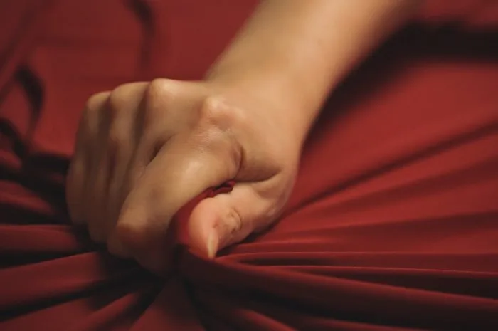 woman hand passionately squeezes red bed sheet love concept