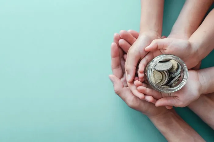 child and parent hands holding money jar, donation, saving, family finance plan concept