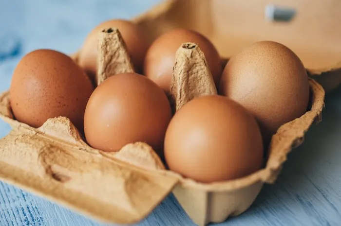 eggs background closeup view of eggs in carton box on wooden table food and health concept