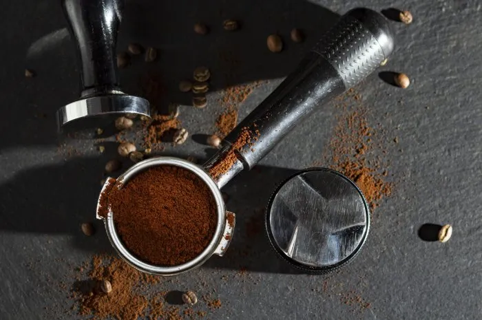 portafilter with coffee and temper on table