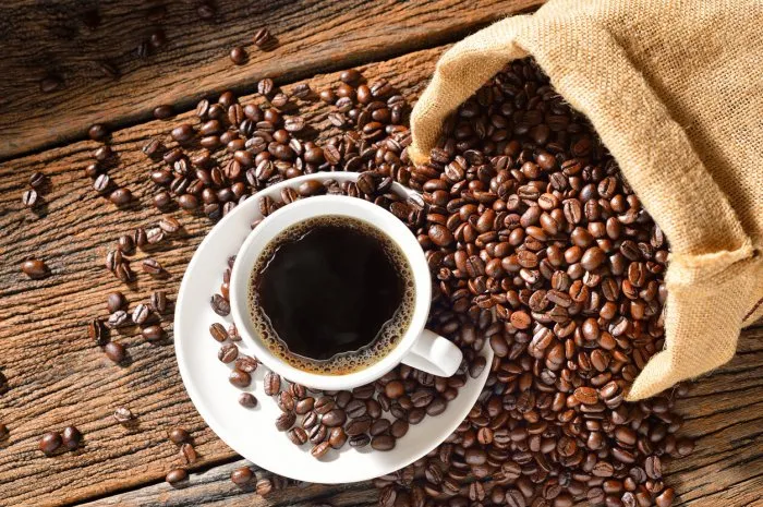 cup of coffee and coffee beans on wooden table