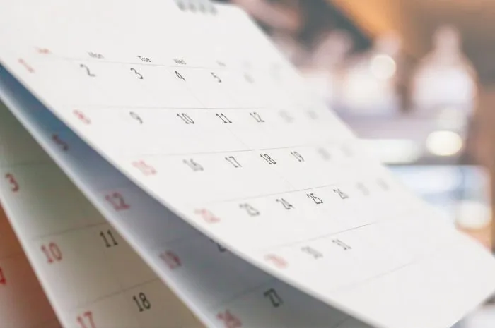 close up white paper desk calendar with blurred bokeh background appointment and business meeting concept