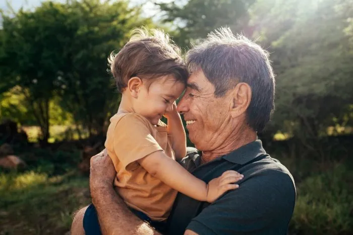playful grandfather spending time with his grandson in park on sunny day