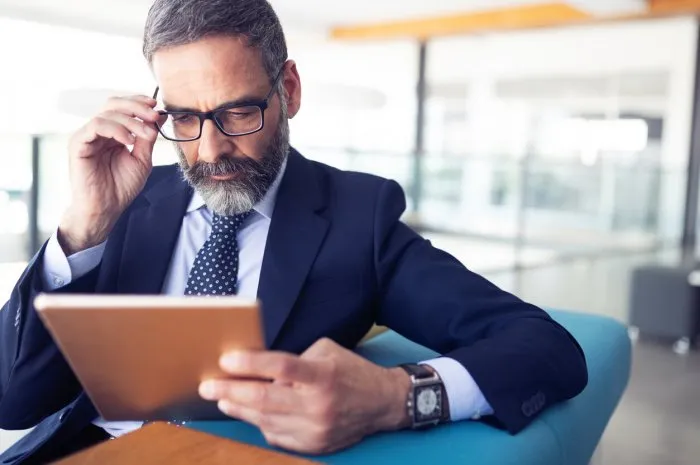 serious man managing director of big prosperous company is holding touch pad