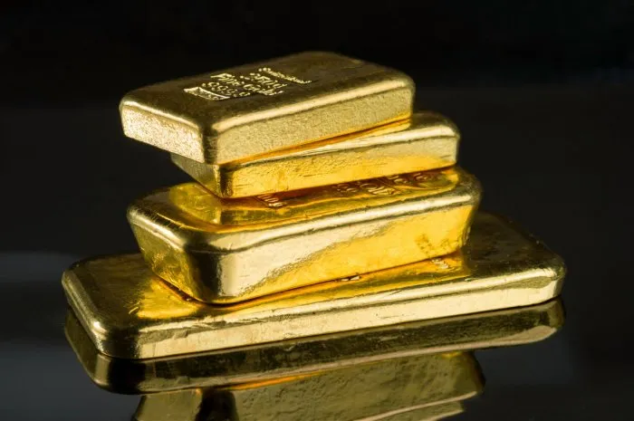 several gold bars of different weight on a dark mirror surface