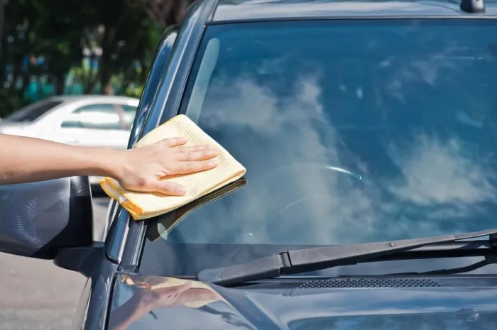 cleaning car windshield , closeup picture service mechanic cleaning car