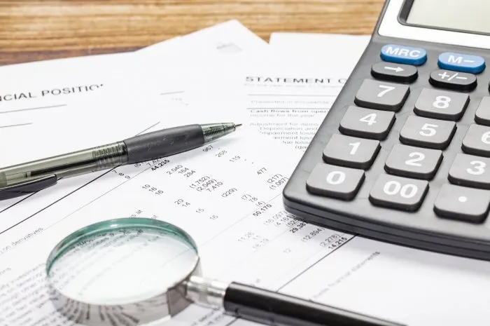 cash flow statement with calculator, pen and hand glass