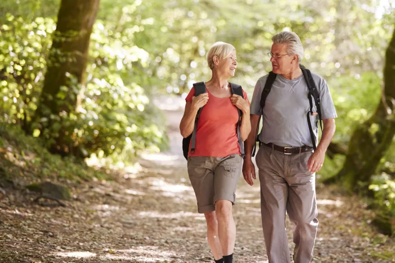 senior couple hiking along woodland path in lake district uk together