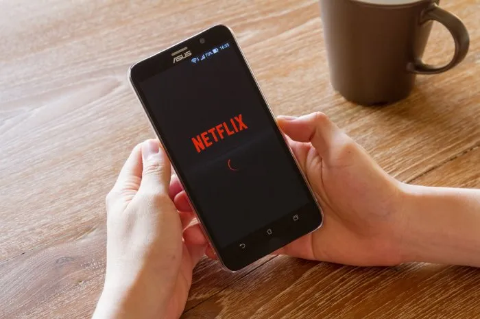 chiang mai, thailand - april 26, 2016  man hand holding screen shot of netflix application showing on asus zenfone 2 mobile phone netflix is a global provider of streaming movies and tv series