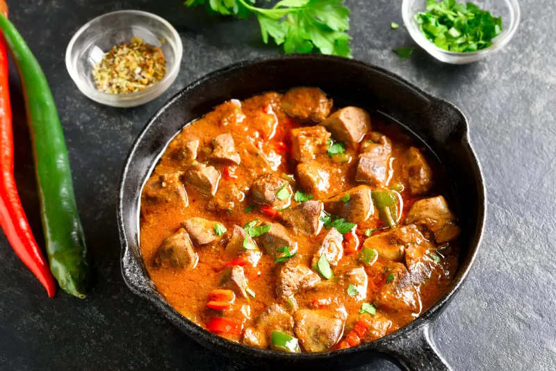 close up view of peri-peri chicken livers in frying pan over dark stone background
