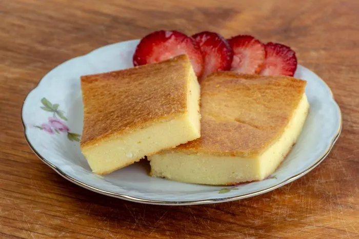 two pieces of fiadone - corsican cheesecake, on a saucer with strawberry slices