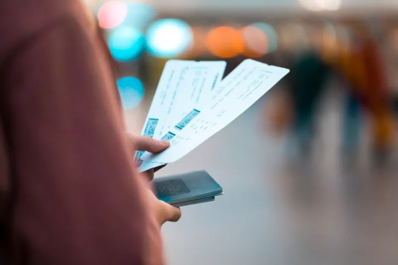 a young girl is going on a trip, holds plane tickets in her hands and goes to check-in, boarding a flight, close-up view of a boarding pass on a blurred background