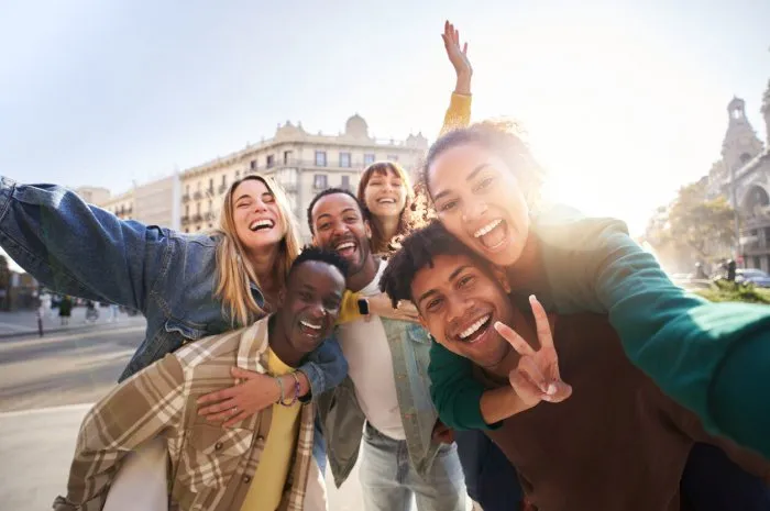 a group of cheerful students college friends having fun together as they travel through european cities happy community of diverse people selective focus on the smily couple taking the selfie
