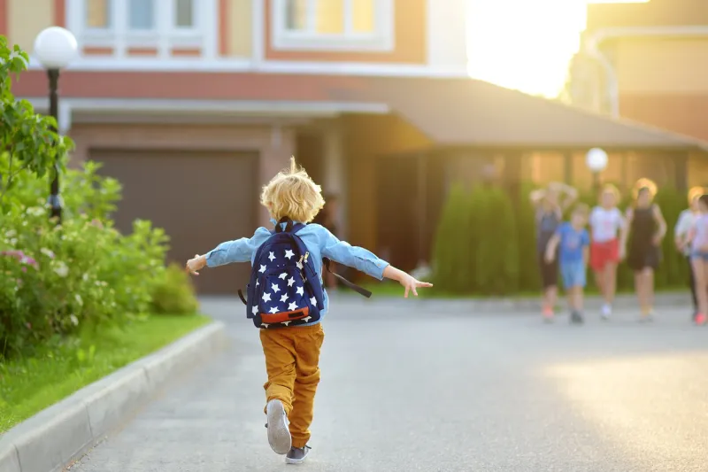 little schoolboy joyfully running to school after holiday child meeting with friends education for children back to school concept kids friendship