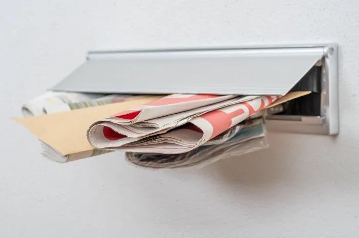 a letter and newspapers in a letterbox