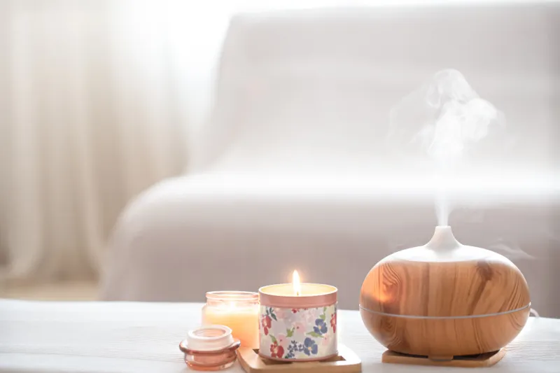 modern oil aroma diffuser in the living room on the table with burning candles the concept of refreshing and purifying the air in the house