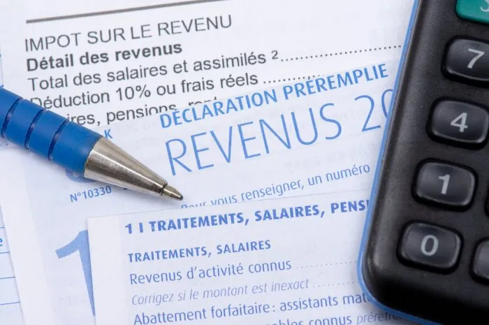 french pre-filled income tax return with the page about income from salaries, treatments, pensions and annuities, along with a pen and a calculator