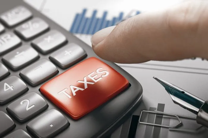 finger about to press a calculator key with the text taxes tax calculation concept composite image between a hand photography and a 3d background