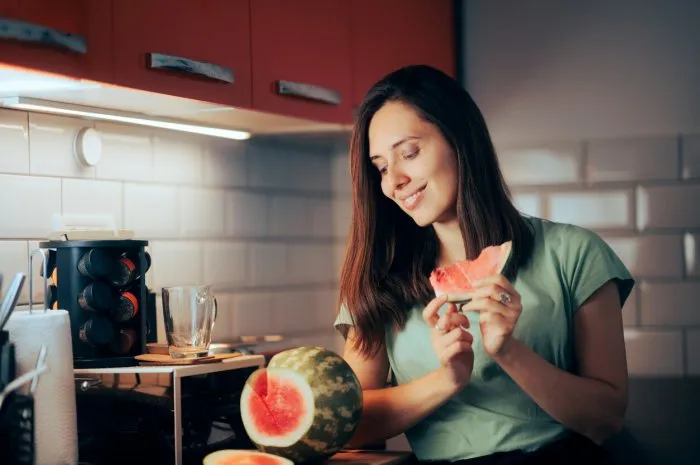 hungry lady having a fruit snack in her kitchen
