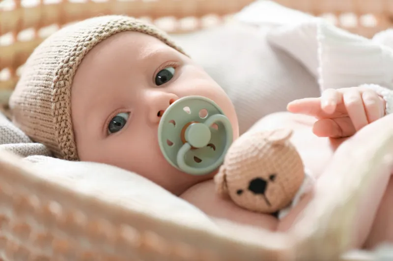 cute newborn baby on white blanket in wicker crib, closeup