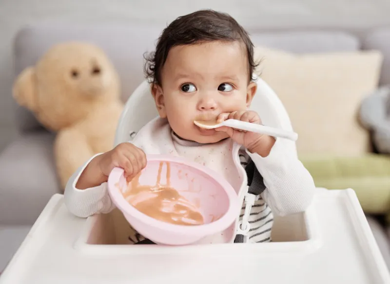 shot of a baby eating a meal at home