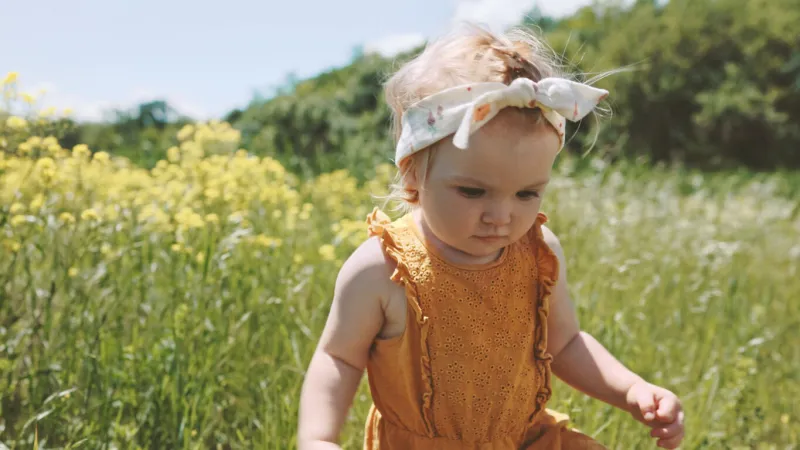 cute baby girl walking outdoor children fashion clothing family travel vacations summer season nature rural field grass