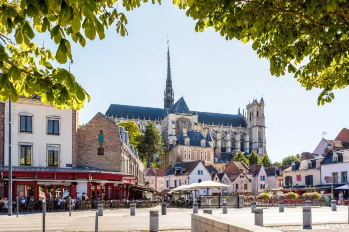 amiens, france - august 13, 2022  general view of notre-dame d'amiens cathedral overlooking the don square lined with historic townhouses, sidewalk cafes and restaurants on a sunny summer day
