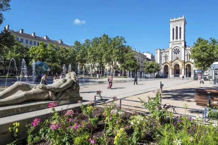saint-etienne, france - july 29, 2019 the square of jean jaures in saint etienne downtown with fountains morini andre catholic church is at right background