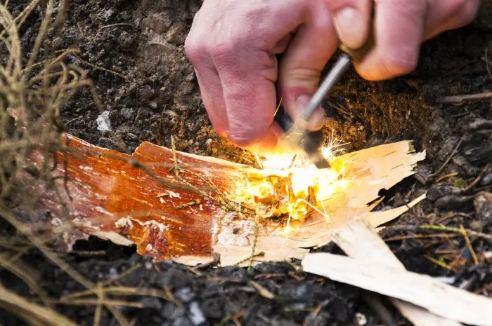 male hand starts fire with magnesium fire steel, fire striker