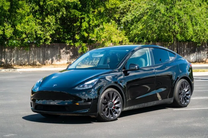 austin , usa - march, 5th, 2022  a tesla model y performance edition in a parking lot with green trees in the background