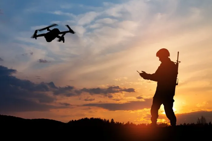 silhouette of soldier are using drone and laptop computer for scouting during military operation against the backdrop of a sunset greeting card for veterans day, memorial day, independence day